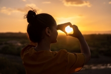 A woman is doing a heart sign towards the sign.